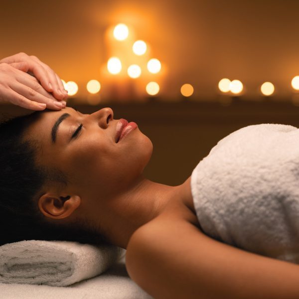 Indian spa massage in romantic atmosphere for black woman, spa salon lighted with candles interior